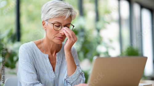 Senior woman rubbing eyes while using laptop in home office