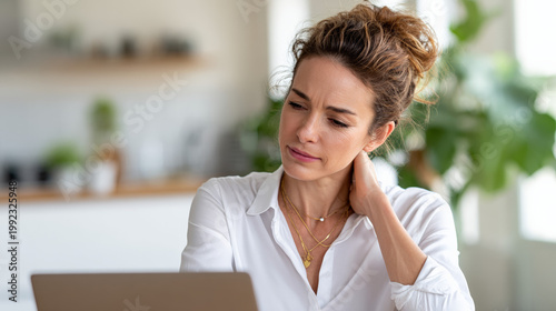 Free Download Woman touching neck while looking at laptop in modern kitchen - GFXLoad