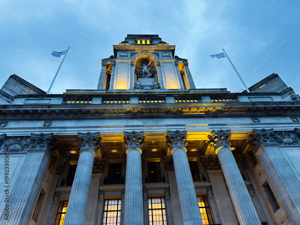 Obraz premium Historic neoclassical civic building with grand columns and illuminated facade in London, UK at dusk. Four Seasons Hotel London at Ten Trinity Square.