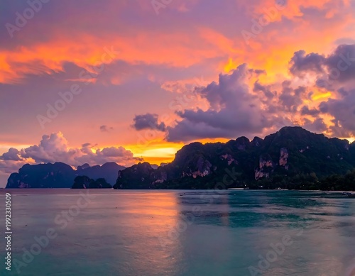 Tropical Island Sunset Landscape With Vibrant Orange And Pink Clouds Reflecting On Calm Turquoise Sea Water And Dark Limestone Cliffs In Thailand