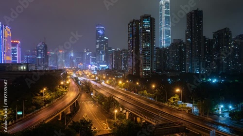 Cityscape at night with blurred red tail lights on highway, lit buildings in the background