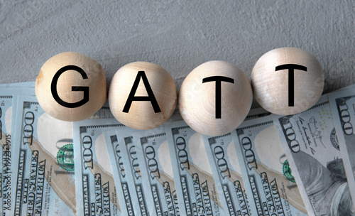 GATT - word on wooden balls on the background of banknotes
