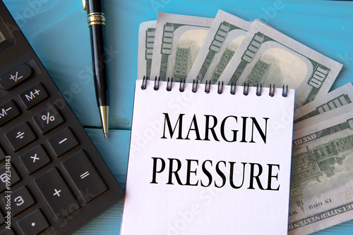MARGIN PRESSURE - words in a notebook on a blue background with banknotes, a calculator and a pen