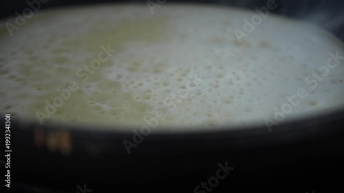 Pancake surface cooking in pan during indoor breakfast preparation.