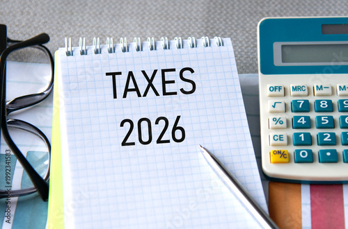 TAXES 2026 - words in a notebook with a calculator, glasses and pen in the background