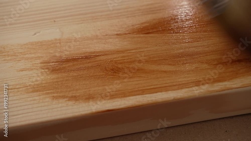 Brush spreads fresh stain along wooden edge during indoor renovation work.