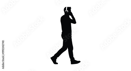 A solitary figure walks while talking on a phone and wearing headphones captured as a stark silhouette high quality professional detailed