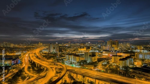 Overpass winds through illuminated city at dusk, beneath a dramatic sky