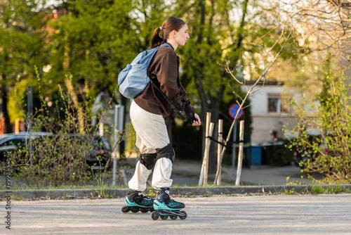Side View Of Teen Girl Roller Skating On Sidewalk