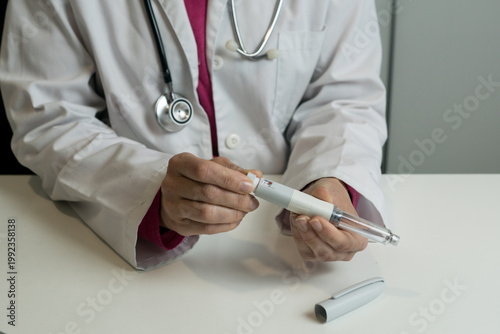 A doctor in a white lab coat showing how to adjust and prepare an insulin injection pen for diabetes treatment.