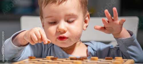 Toddler playing checkers at home, exploring strategy and logic.