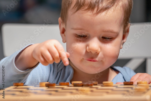 Little boy concentrating on checkers board, developing thinking and attention skills.