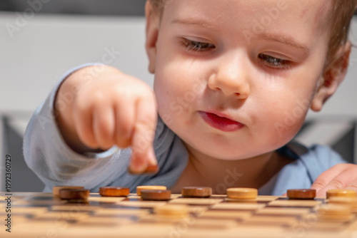 Little boy with checkers pieces, early development of strategic thinking.