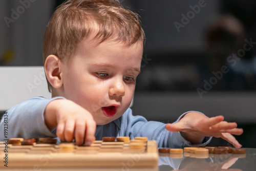 Little child playing checkers, building patience and focus from early age.