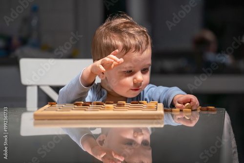 Adorable kid playing draughts at home, concept of early education and development.