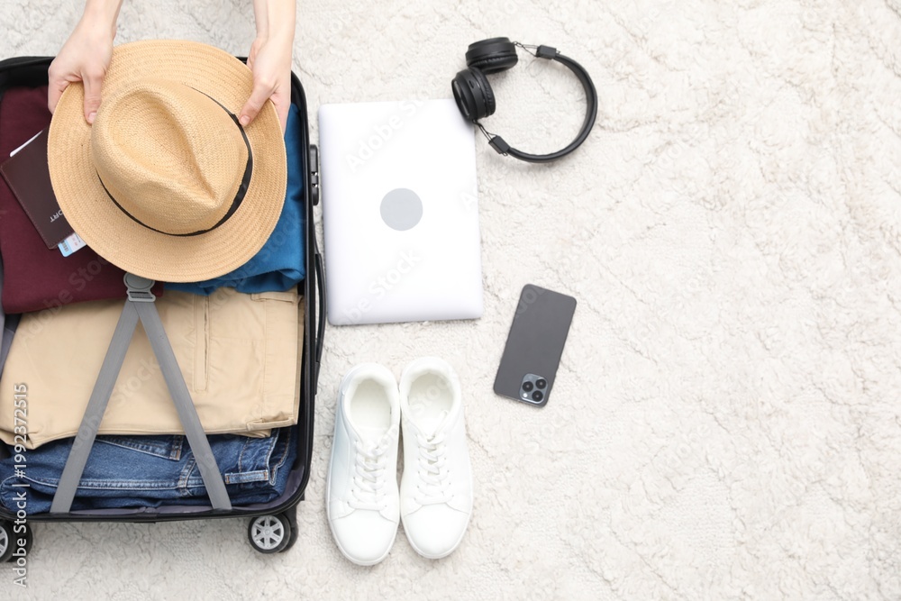 Naklejka premium Woman packing suitcase for trip indoors, top view