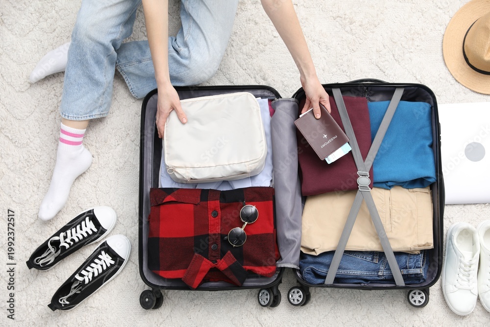 Obraz premium Woman packing suitcase for trip indoors, top view