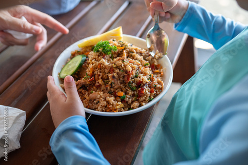 Child Enjoying a Plate of Seafood Fried Rice with Fresh Vegetables and Lemon