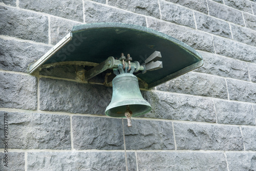 Historic Bell Mounted on Stone Wall in Urban Setting, Showcasing Architectural Detail and Cultural Significance