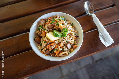 Delicious Seafood Noodle Bowl with Fresh Vegetables and Lime on a Wooden Table