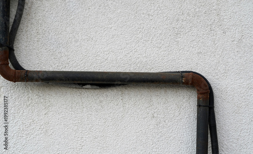 Close-up of an old rusty metal pipe mounted on a wall. Corrosion and weathered texture highlight aging infrastructure, ideal for plumbing, industry, maintenance, and urban decay concepts