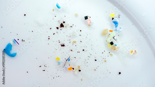 Macro view of microplastic pieces scattered on a Petri dish. A collection of plastic fragments and sediment highlights the global ocean pollution. Micro plastic particles and synthetic debris