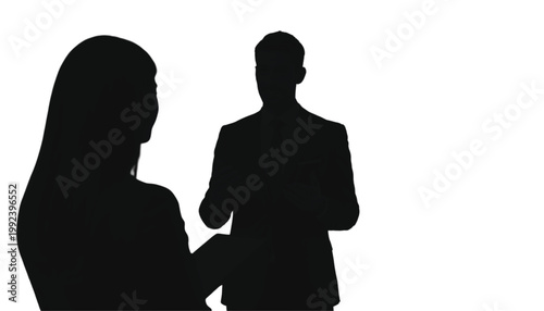 Businessman and businesswoman stand together to discuss a corporate project in a bright white space.