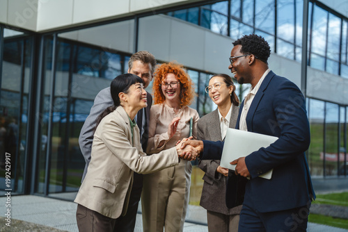 Diverse business team celebrating success with a handshake outside office building