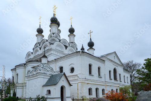 In Murom, a stunning historic church stands tall against the gray sky, featuring ornate architecture and gleaming golden domes that catch the eye.