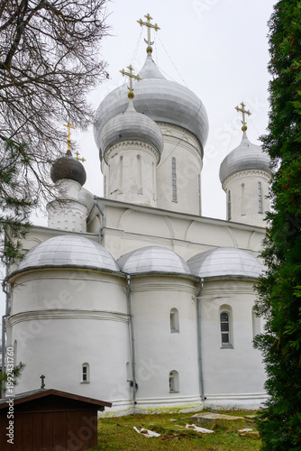 A beautiful church stands proudly in Pereslavl-Zalessky, featuring intricate domes and delicate crosses under a grey sky, surrounded by lush greenery.
