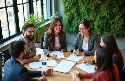 Diverse group of professionals in modern office discusses project at table. Team members collaborate, share ideas, review documents. Business people work together in bright collaborative space with