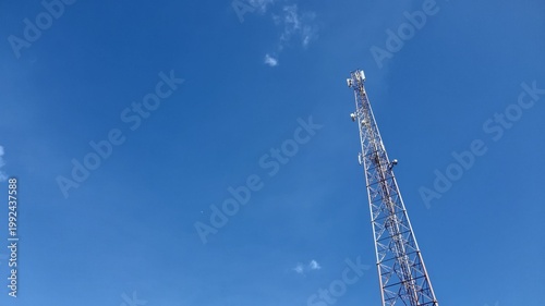 Cuadro en lienzo A tall metal lattice telecommunication tower stands high against a clear blue sk