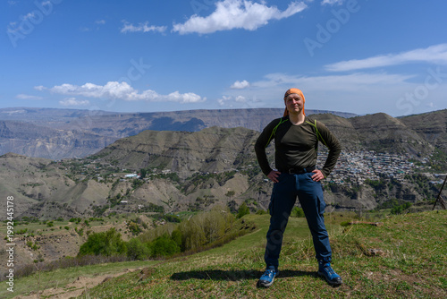 Man standing on a hillside overlooking a mountain village.
