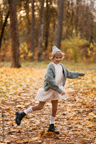 Caucasian Girl Twirling Through Leaf Carpet, Floral Dress And Oversized Cardigan In Motion, Boots Lifting Off Wet Ground, Joyful Energy And Rustling Foliage, Candid Lifestyle Moment