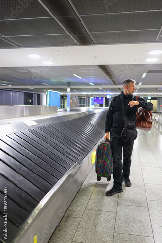 Man arriving at airport with luggage, waiting for baggage and travel concept.