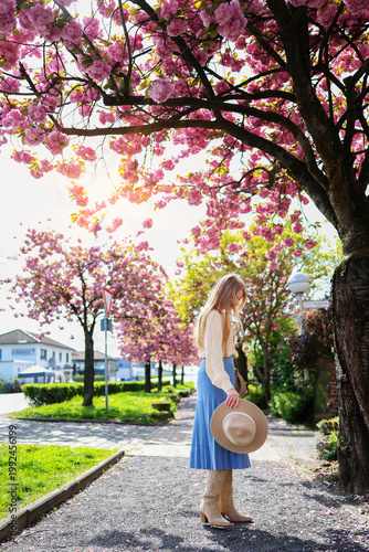 Woman in park under cherry blossoms, vibrant springtime scene and travel inspiration.