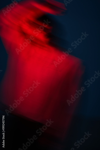 Person moving quickly with red lights in dark setting