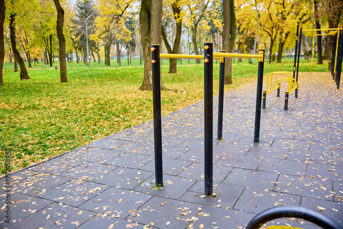 Autumn park outdoor gym with yellow leaves on black rubber surface