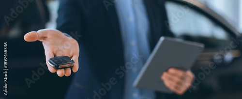 Fotografie A person is handing over a car key to another individual at a dealership