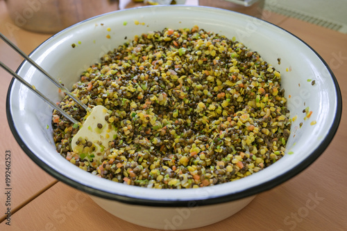 Lentil salad in a white enamel bowl, various types of lentils with small pieces of carrot, leek, and onion, healthy meal, plant-based protein and dietary fiber, selected focus,