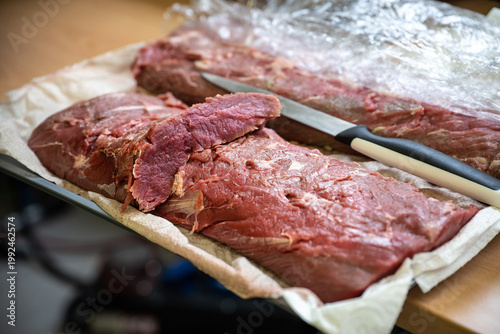 Raw veal loin, preparation in a restaurant for the meat course of a dinner menu with many guests, selected focus