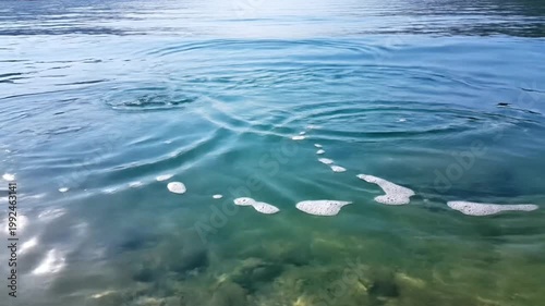 Close-up of water surface with multiple ripples, creating circular patterns with light reflection