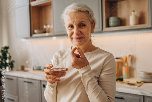 Portrait of positive senior lady takes medical supplements for health care at home