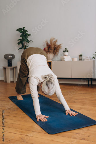 Aged lady pensioner practicing yoga exercise at home studio