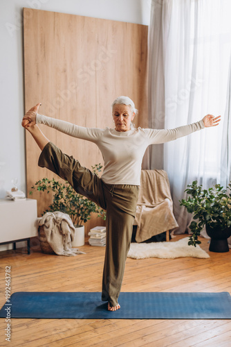 Elderly woman holds high leg extension feeling proud and calm