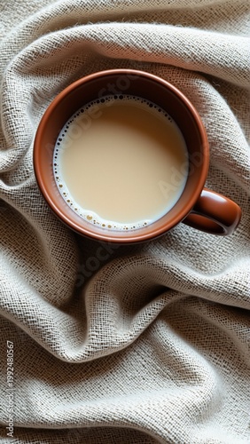 close cup coffee beige fabric cup brown color has handle one side coffee light beige color appears freshly brewed fabric draped over cup creating soft luxurious texture background blurred making cup