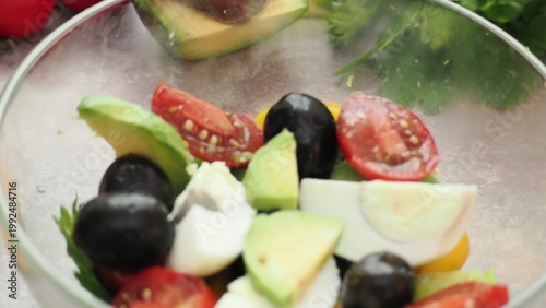 A girl prepares a delicious, low-calorie, and healthy salad. Keto diet. Balanced protein and fat, high in fiber. Salad with avocado, greens, bell pepper, egg, olives, parsley, and dill, tomatoes
