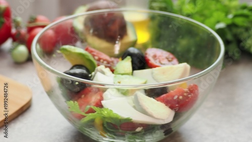 A girl prepares a delicious, low-calorie, and healthy salad. Keto diet. Balanced protein and fat, high in fiber. Salad with avocado, greens, bell pepper, egg, olives, parsley, and dill, tomatoes