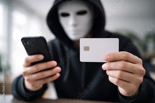 Masked individual committing cybercrime using smartphone and card, highlighting identity theft and digital fraud risks.