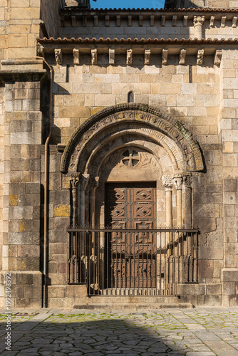 Wallpaper Mural A close-up view of the historic Romanesque stone portal and carved wooden door of the Se de Braga Cathedral in Portugal featuring intricate granite arches and architectural details under sunlight Torontodigital.ca